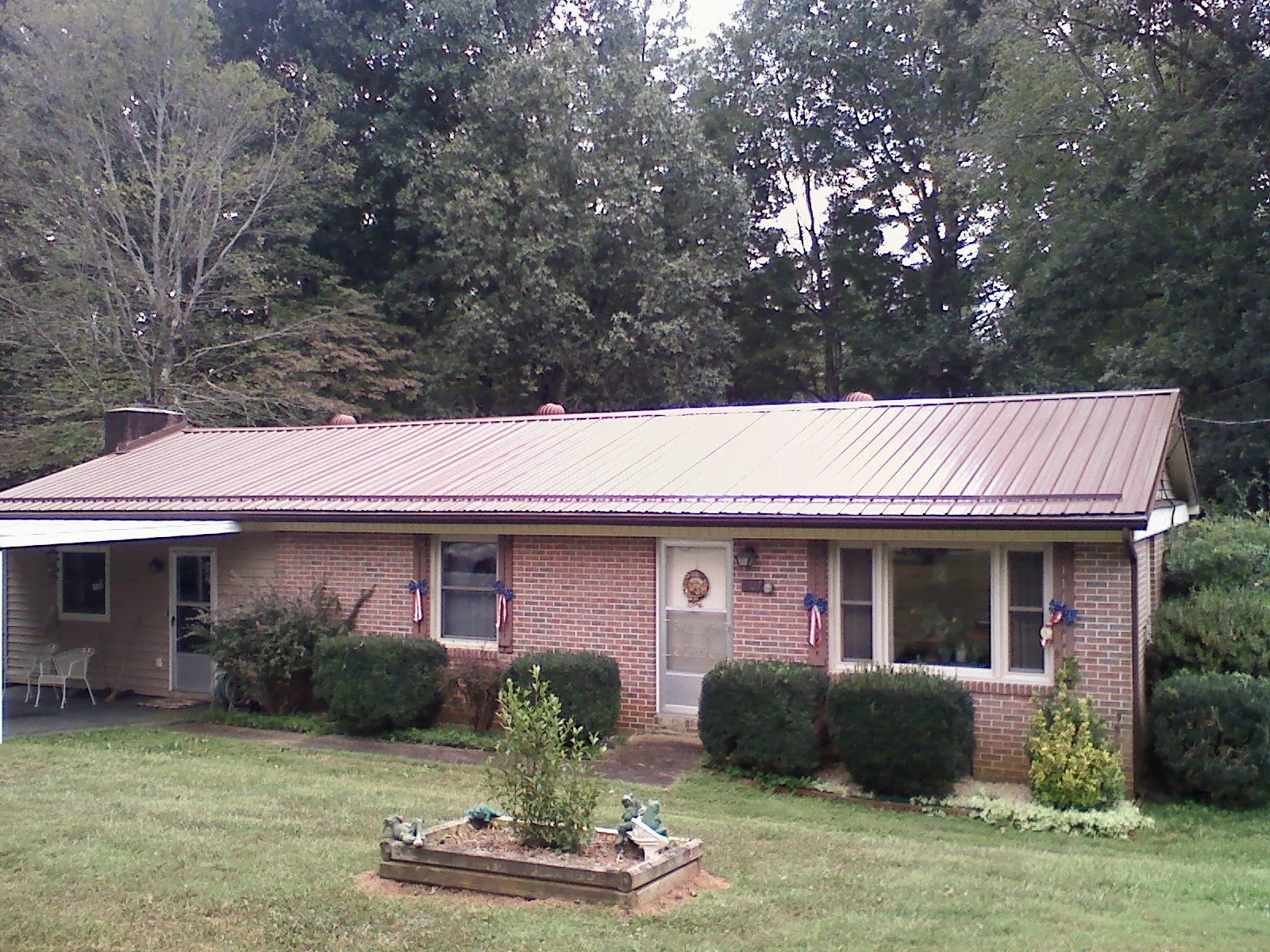 Bronze metal roof on a brick ranch home with a carport in La Grange